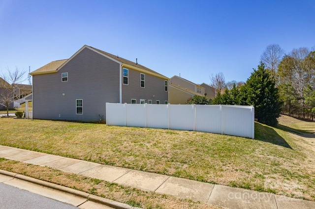 view of side of property featuring fence and a lawn