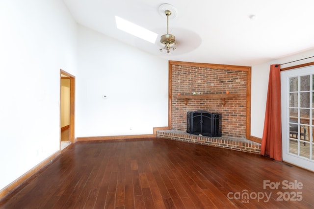 unfurnished living room with lofted ceiling with skylight, a fireplace, baseboards, and wood finished floors