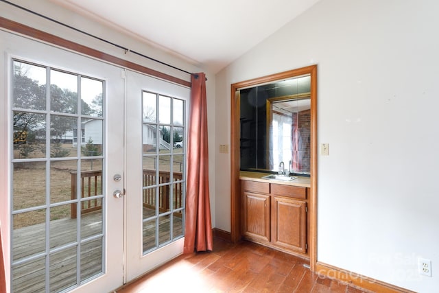 entryway featuring lofted ceiling, wood finished floors, a sink, french doors, and indoor wet bar