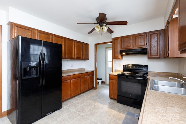 kitchen with black appliances, a sink, light countertops, and under cabinet range hood