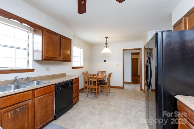 kitchen featuring black appliances, pendant lighting, brown cabinets, and a sink