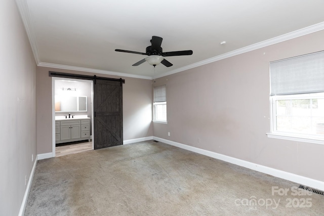 unfurnished bedroom featuring a barn door, baseboards, visible vents, crown molding, and carpet flooring