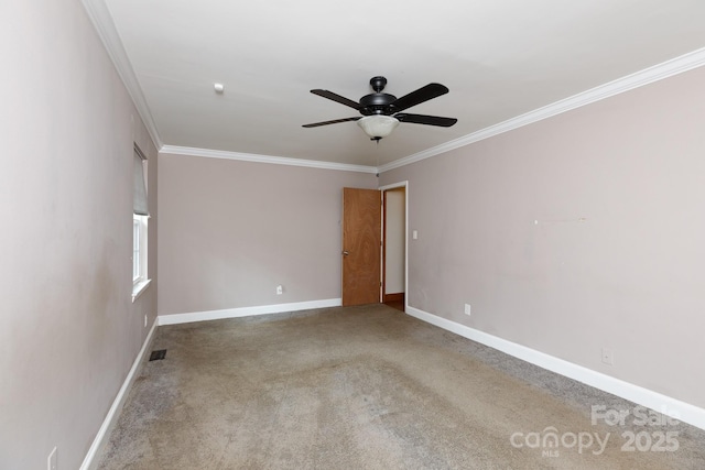 carpeted empty room with a ceiling fan, baseboards, visible vents, and crown molding