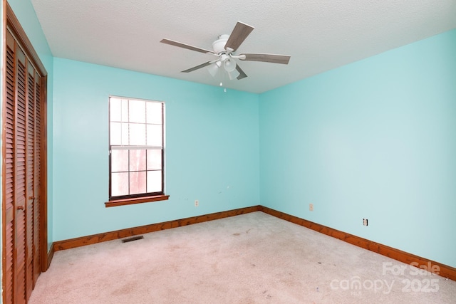 unfurnished room with carpet floors, baseboards, visible vents, and a textured ceiling