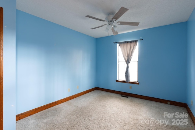 empty room with ceiling fan, carpet floors, visible vents, and baseboards