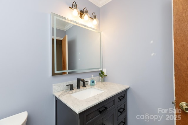 bathroom with toilet, crown molding, and vanity