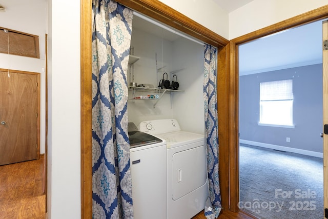 laundry room with washing machine and clothes dryer, ornamental molding, wood finished floors, laundry area, and baseboards