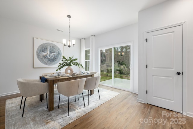 dining area with an inviting chandelier, visible vents, wood finished floors, and baseboards