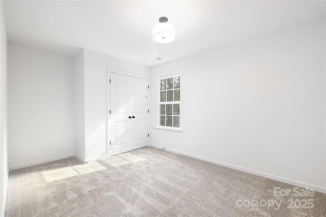 empty room featuring light colored carpet and baseboards