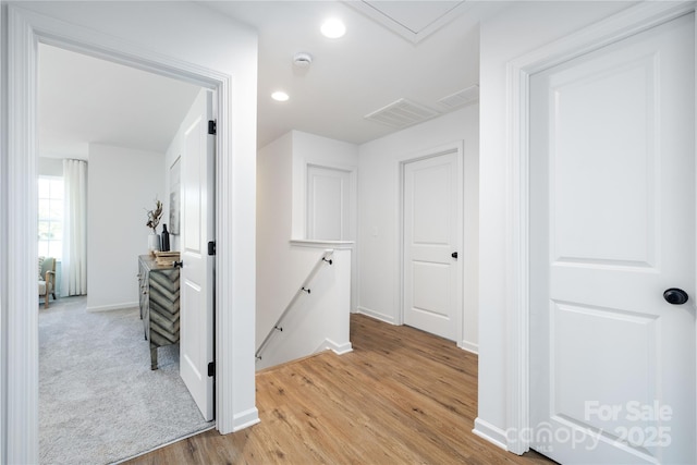 hallway with light wood finished floors, baseboards, an upstairs landing, and recessed lighting