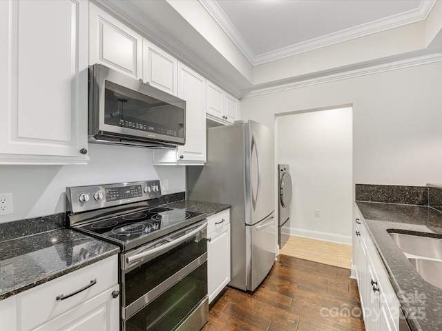 kitchen with stainless steel appliances, dark wood-type flooring, ornamental molding, white cabinetry, and washer and dryer