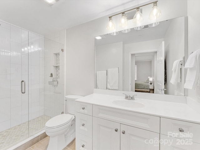 ensuite bathroom featuring toilet, ensuite bathroom, a stall shower, vanity, and tile patterned floors