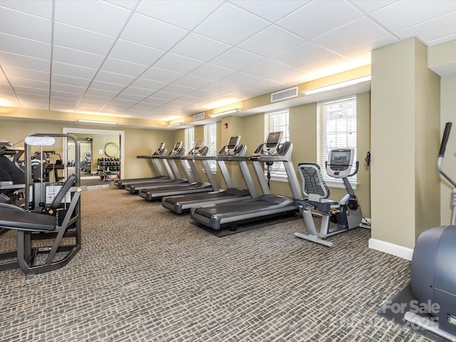 exercise room featuring a paneled ceiling, baseboards, visible vents, and carpet flooring