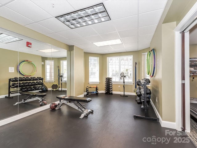 exercise room featuring a drop ceiling and baseboards