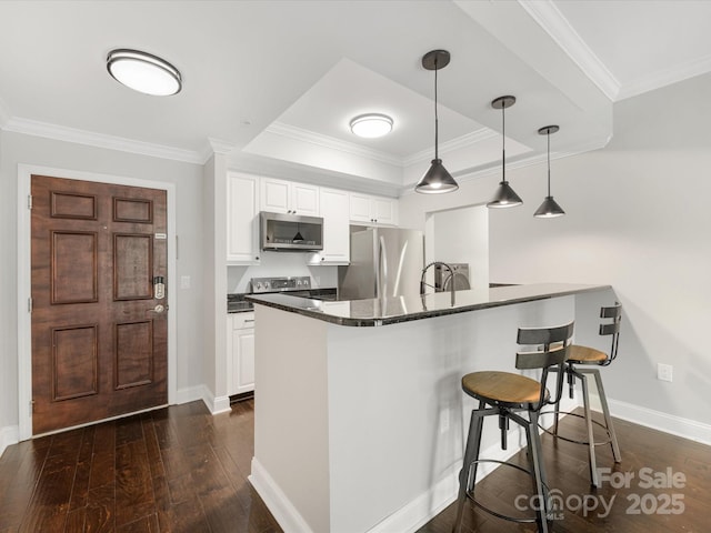 kitchen featuring white cabinetry, crown molding, appliances with stainless steel finishes, and a breakfast bar area