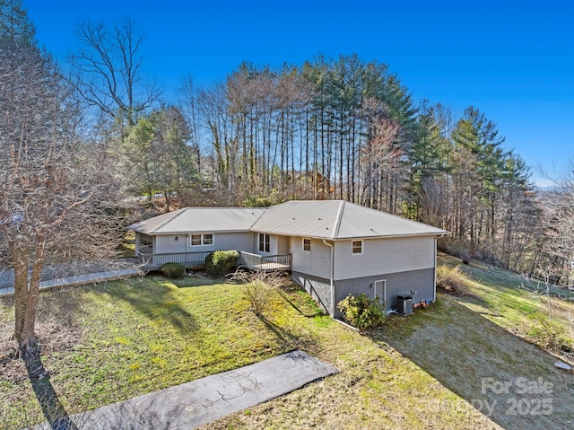 view of front of house with a deck, metal roof, cooling unit, driveway, and a front yard