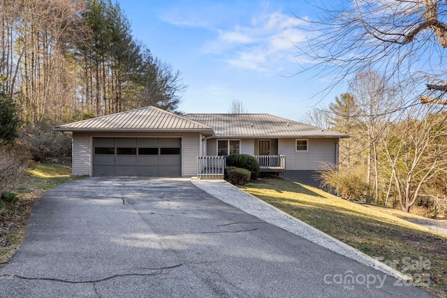 ranch-style home featuring aphalt driveway, covered porch, an attached garage, metal roof, and a front lawn