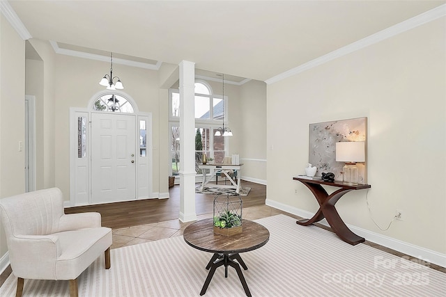 entryway featuring tile patterned flooring, crown molding, a notable chandelier, and baseboards