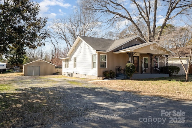 view of front facade featuring covered porch, crawl space, a garage, driveway, and an outdoor structure