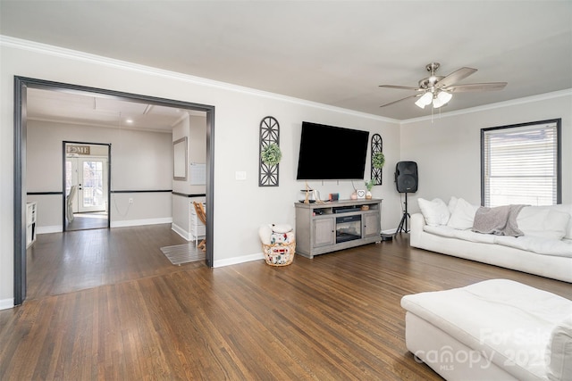 living area with baseboards, ornamental molding, dark wood finished floors, and a ceiling fan