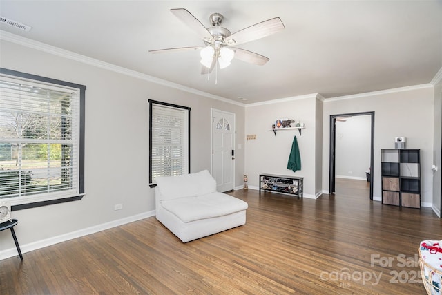 living area with baseboards, crown molding, visible vents, and wood finished floors