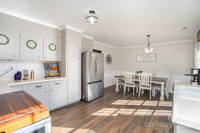 kitchen with dark wood-style floors, crown molding, light countertops, freestanding refrigerator, and white cabinetry