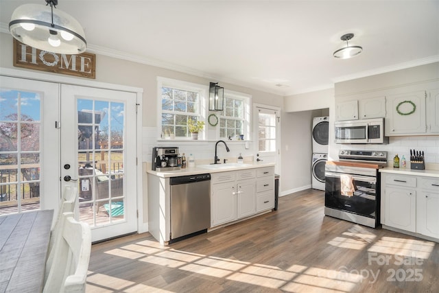 kitchen featuring stainless steel appliances, a sink, light countertops, french doors, and stacked washer and clothes dryer