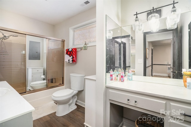 bathroom featuring toilet, wood finished floors, vanity, visible vents, and combined bath / shower with glass door