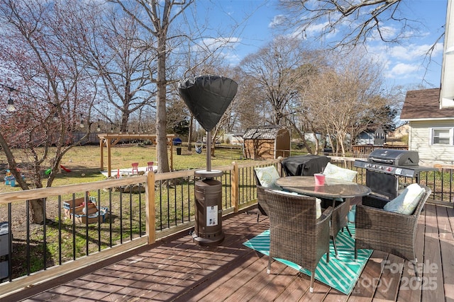 deck with an outbuilding, a grill, outdoor dining area, a yard, and a shed