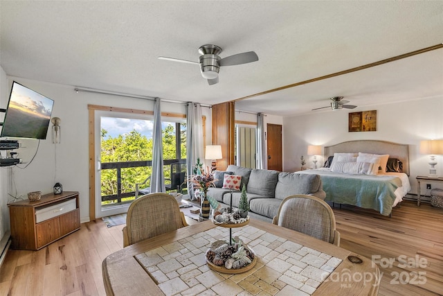 bedroom featuring ceiling fan, access to outside, a textured ceiling, light wood-style floors, and a baseboard heating unit