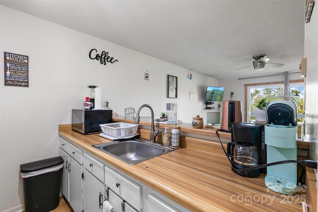 kitchen featuring black microwave, light countertops, ceiling fan, and a sink