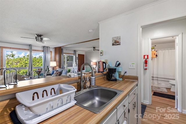 kitchen with light countertops, open floor plan, a sink, a textured ceiling, and ceiling fan