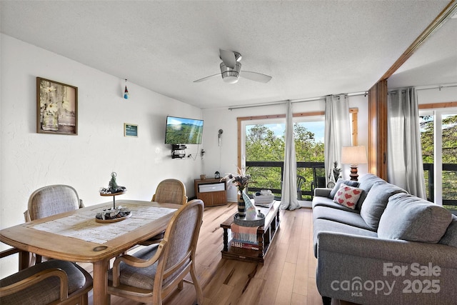 dining area with a textured ceiling, light wood finished floors, vaulted ceiling, and a ceiling fan