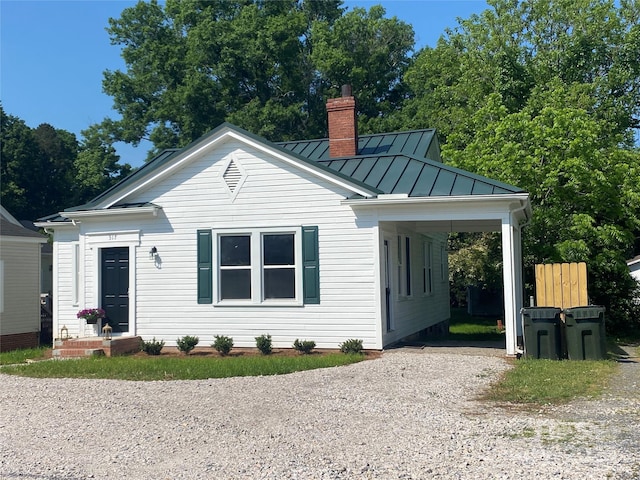bungalow featuring a standing seam roof, metal roof, a chimney, driveway, and a carport