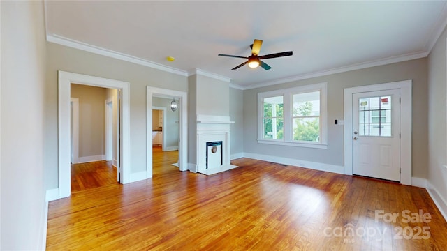 unfurnished living room with crown molding, light wood-style flooring, ceiling fan, and baseboards
