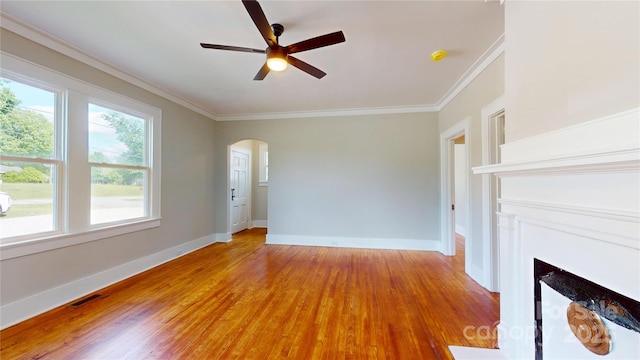 unfurnished living room featuring visible vents, arched walkways, crown molding, and light wood-type flooring
