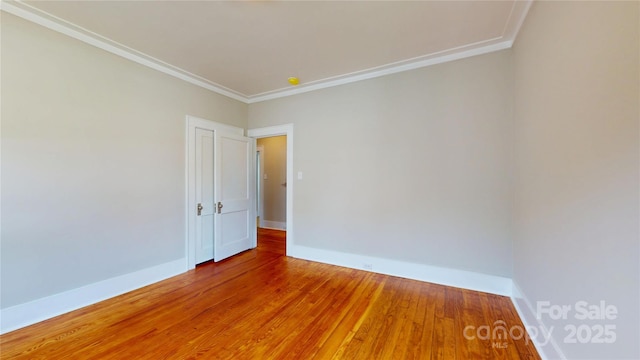 unfurnished room with crown molding, baseboards, and wood finished floors