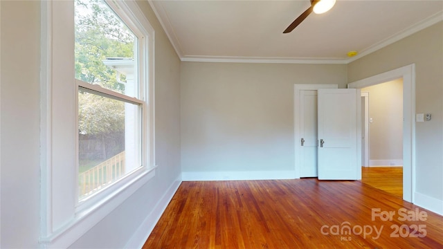 empty room featuring crown molding, baseboards, a ceiling fan, and wood finished floors