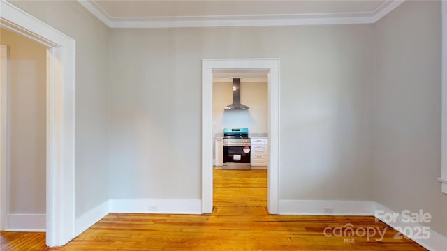 unfurnished room featuring light wood-style floors, baseboards, and crown molding