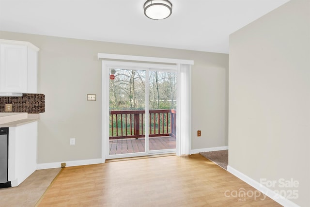 unfurnished dining area featuring baseboards and light wood-style floors