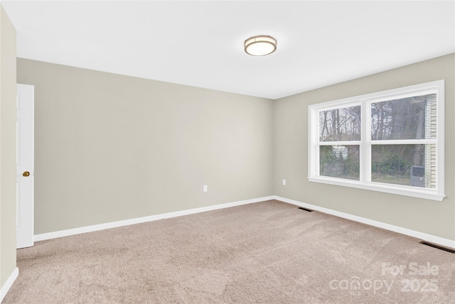 carpeted spare room featuring visible vents and baseboards