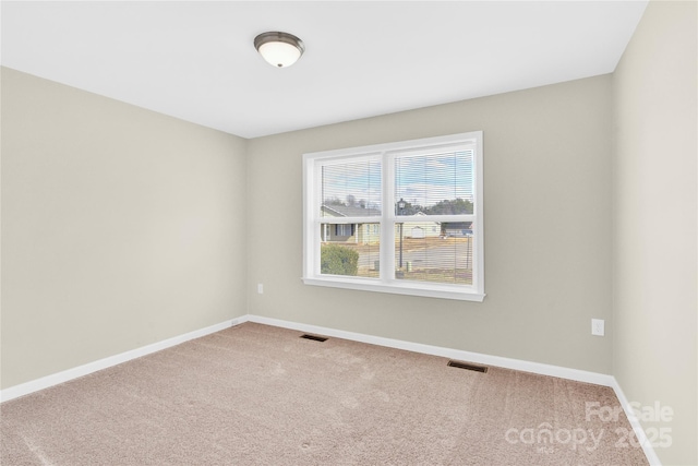 carpeted spare room featuring visible vents and baseboards