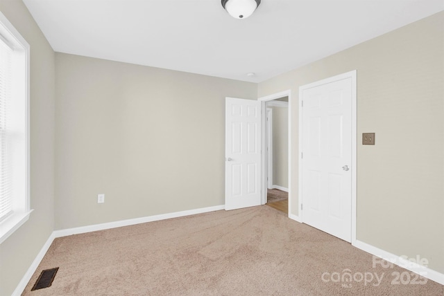 unfurnished bedroom with carpet, visible vents, and baseboards