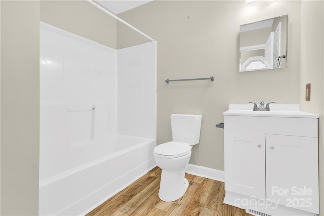 bathroom with baseboards, toilet, vanity, wood finished floors, and shower / bathtub combination