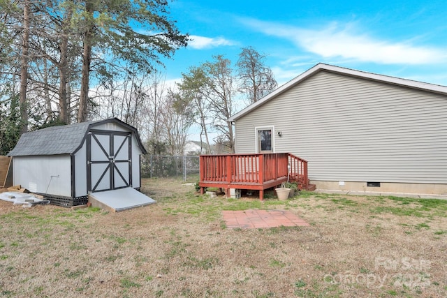 view of yard with a storage shed, a wooden deck, fence, and an outbuilding