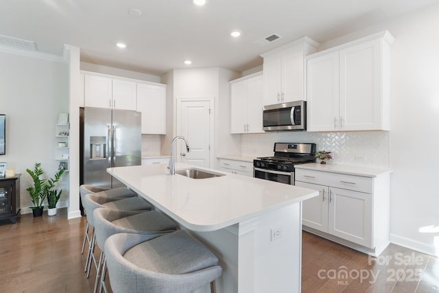 kitchen featuring a sink, visible vents, appliances with stainless steel finishes, and a center island with sink