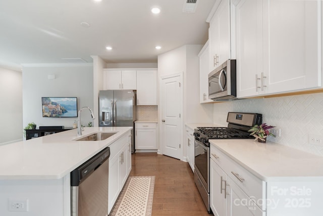 kitchen featuring visible vents, appliances with stainless steel finishes, wood finished floors, white cabinetry, and a sink