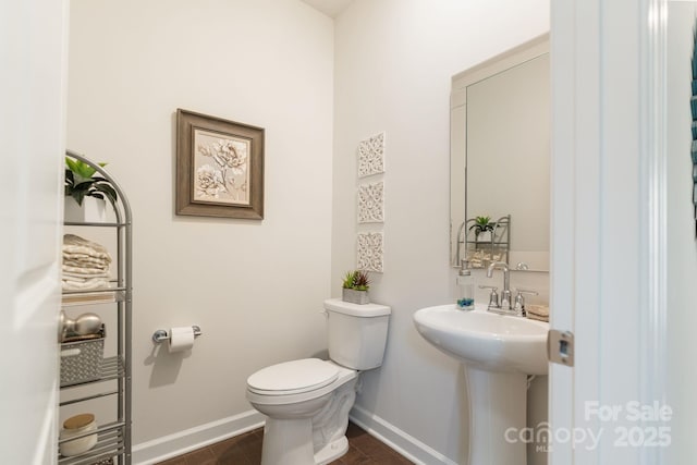 bathroom with toilet, baseboards, and a sink