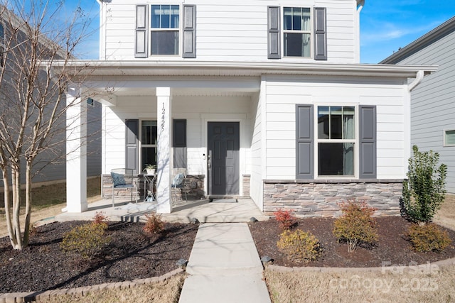 doorway to property with covered porch and stone siding