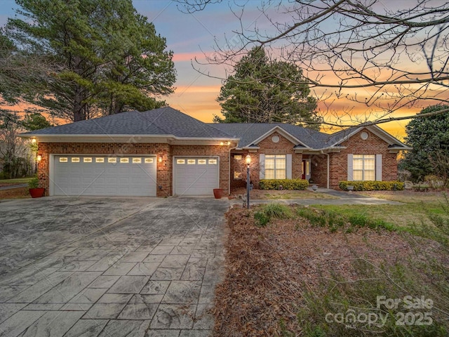 view of front of house with brick siding, concrete driveway, a garage, and roof with shingles